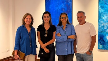 Cuatro personas posan juntas en una galería de arte frente a dos pinturas de color azul colgadas en la pared