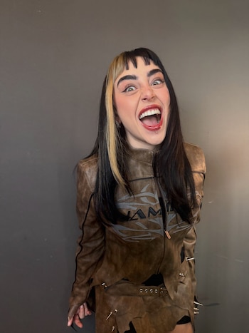 Nicki Nicole muestra su nuevo corte de cabello con flequillo recto y melena oscura mientras posa con los ojos entrecerrados y los labios pintados de rojo.
