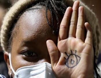 Una joven muestra su mano con un ojo dibujado que significa "los estamos mirando", como mensaje a los delegados de la COP26, durante una protesta en Glasgow. REUTERS/Yves Herman
