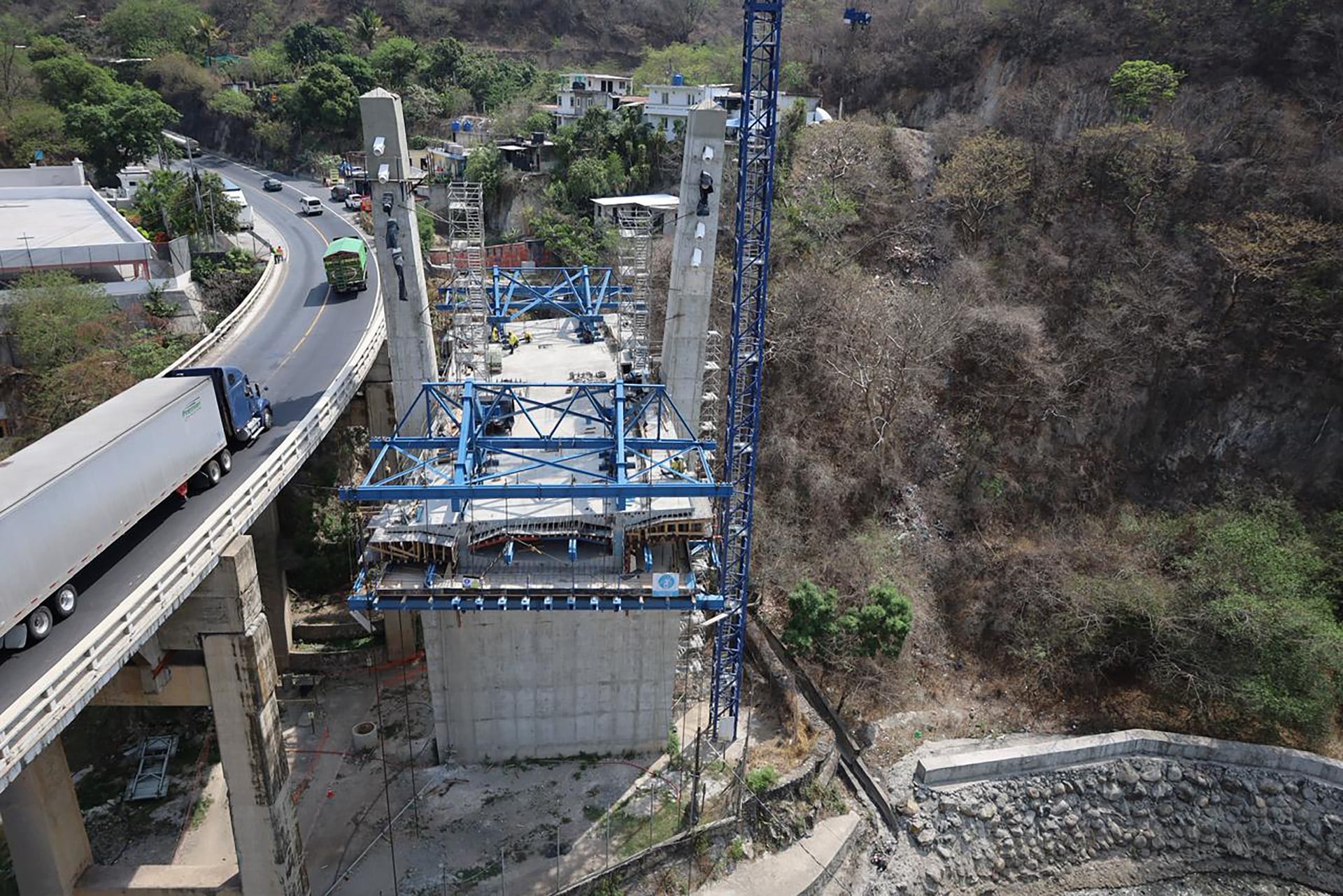 Se observa el avance significativo en la construcción de un nuevo puente vial adyacente a una carretera existente con tráfico, destacando la expansión de la infraestructura regional. (Ministerio de Comunicaciones, Infraestructura y Vivienda)