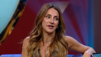 Eleonora Wexler, mujer de cabello castaño y largo, mira a la derecha con boca entreabierta. Viste top escotado y collares. Fondo de estudio con tonos rojizos y azules