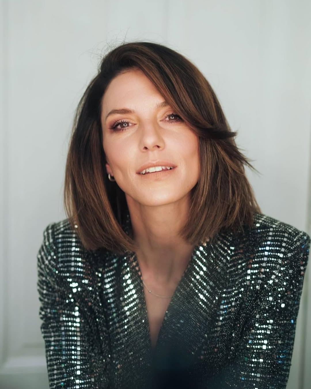 La reconocida actriz Manuela Pal posa elegantemente con un blazer de lentejuelas, destacando su sofisticado estilo en este retrato.