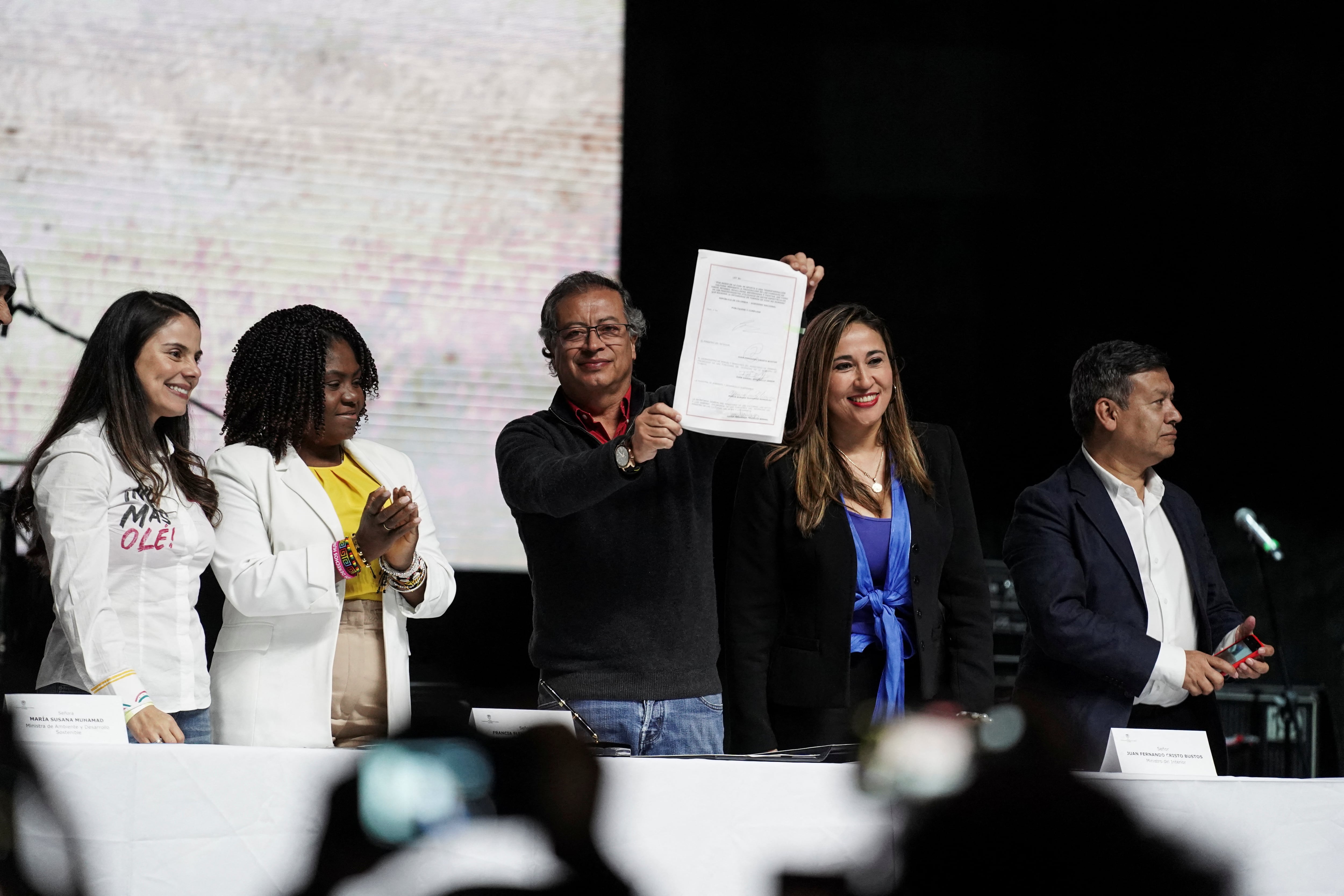 Colombian President Gustavo Petro holds the bill signed to announce the approval of a law called
