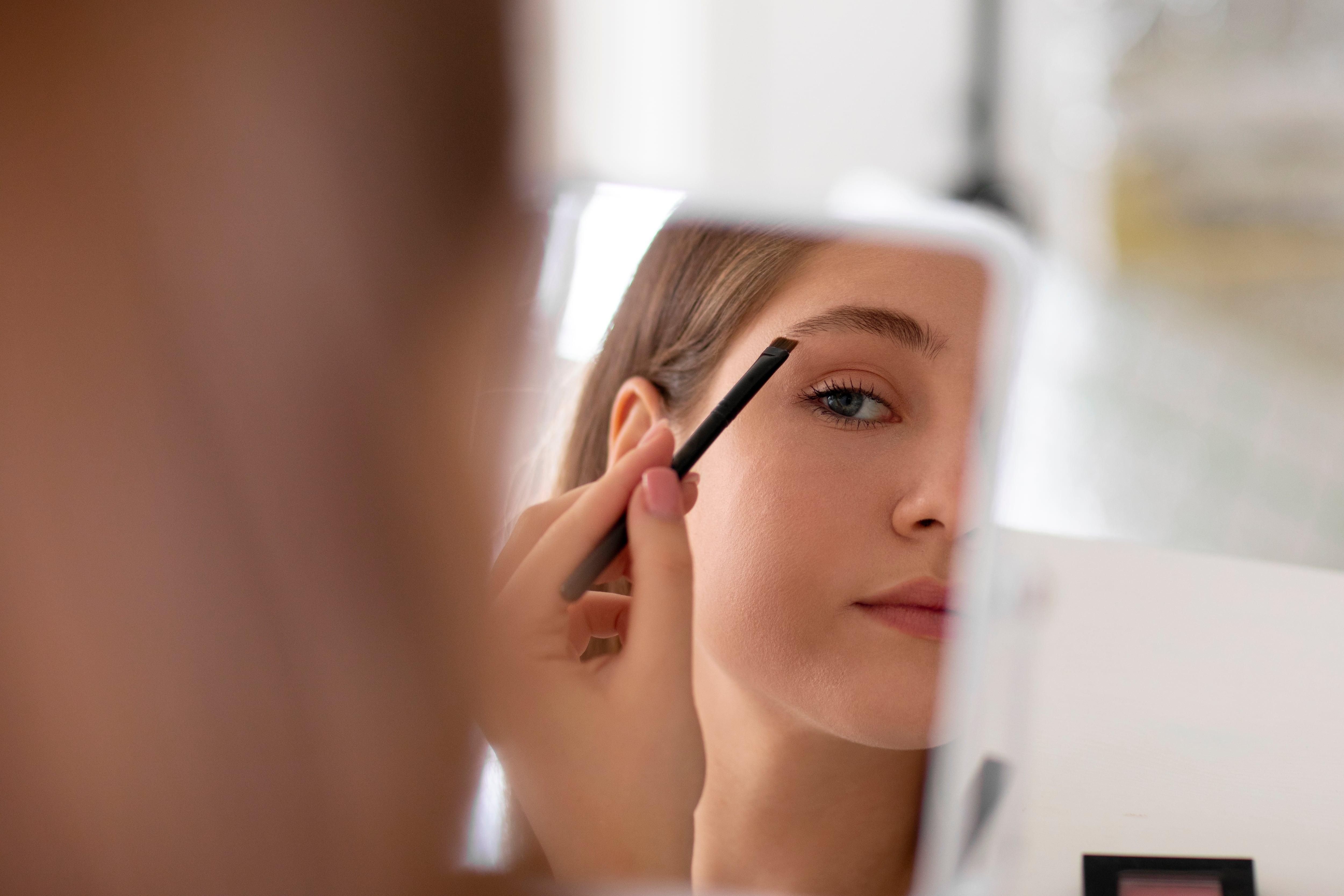 Una mujer se perfila las cejas (Magnific)