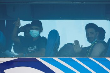 Migrantes gesticulan desde un autobús