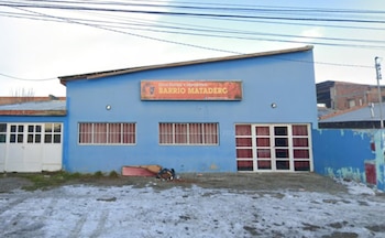 Edificio azul con cartel naranja que dice 'Club Social y Deportivo Barrio Matadero'. Cuatro ventanas con rejas, una puerta doble y nieve en el suelo