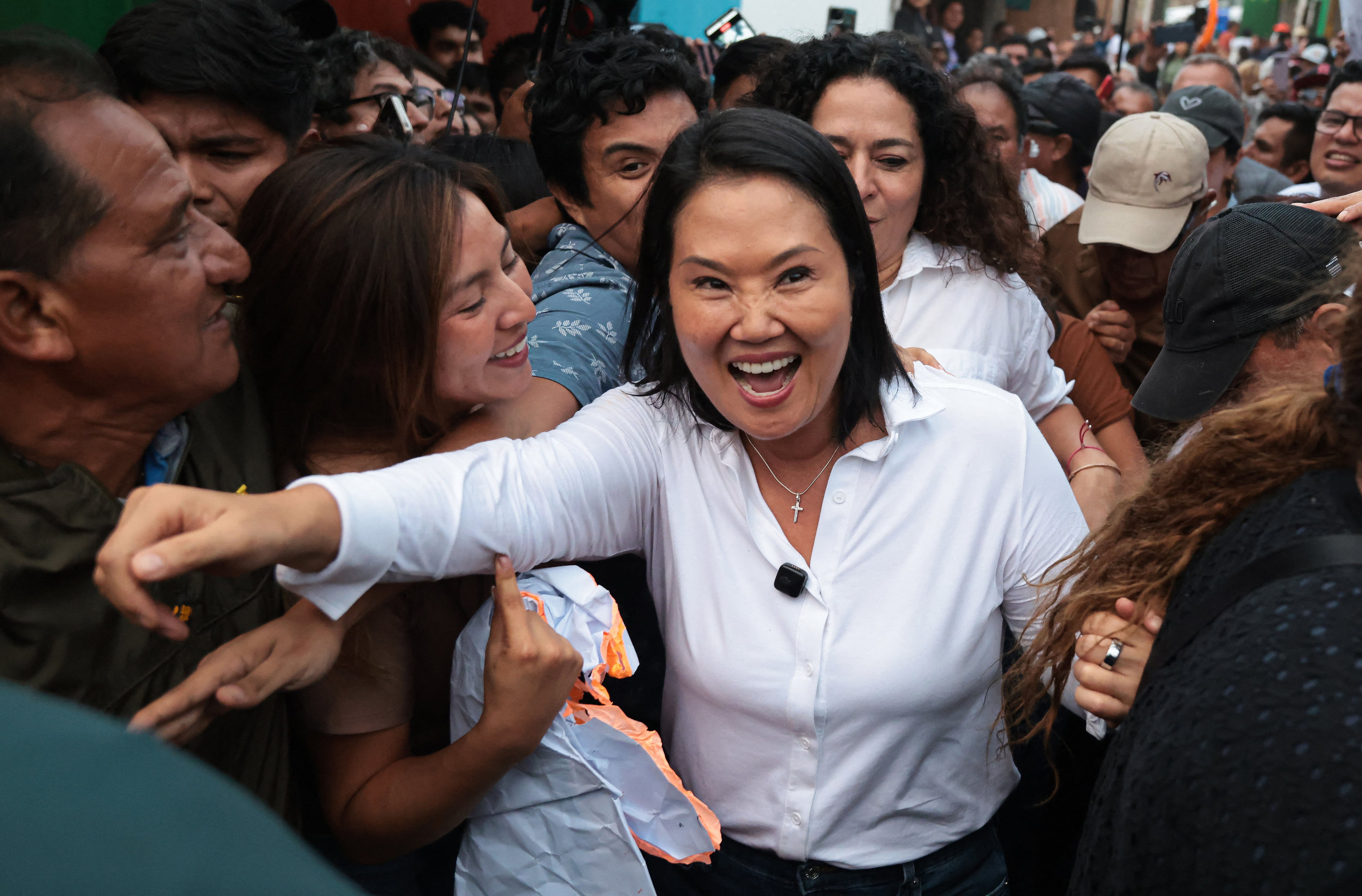 Keiko Fujimori saluda sonriente a sus seguidores en un evento público, rodeada por una multitud que busca acercarse a ella.