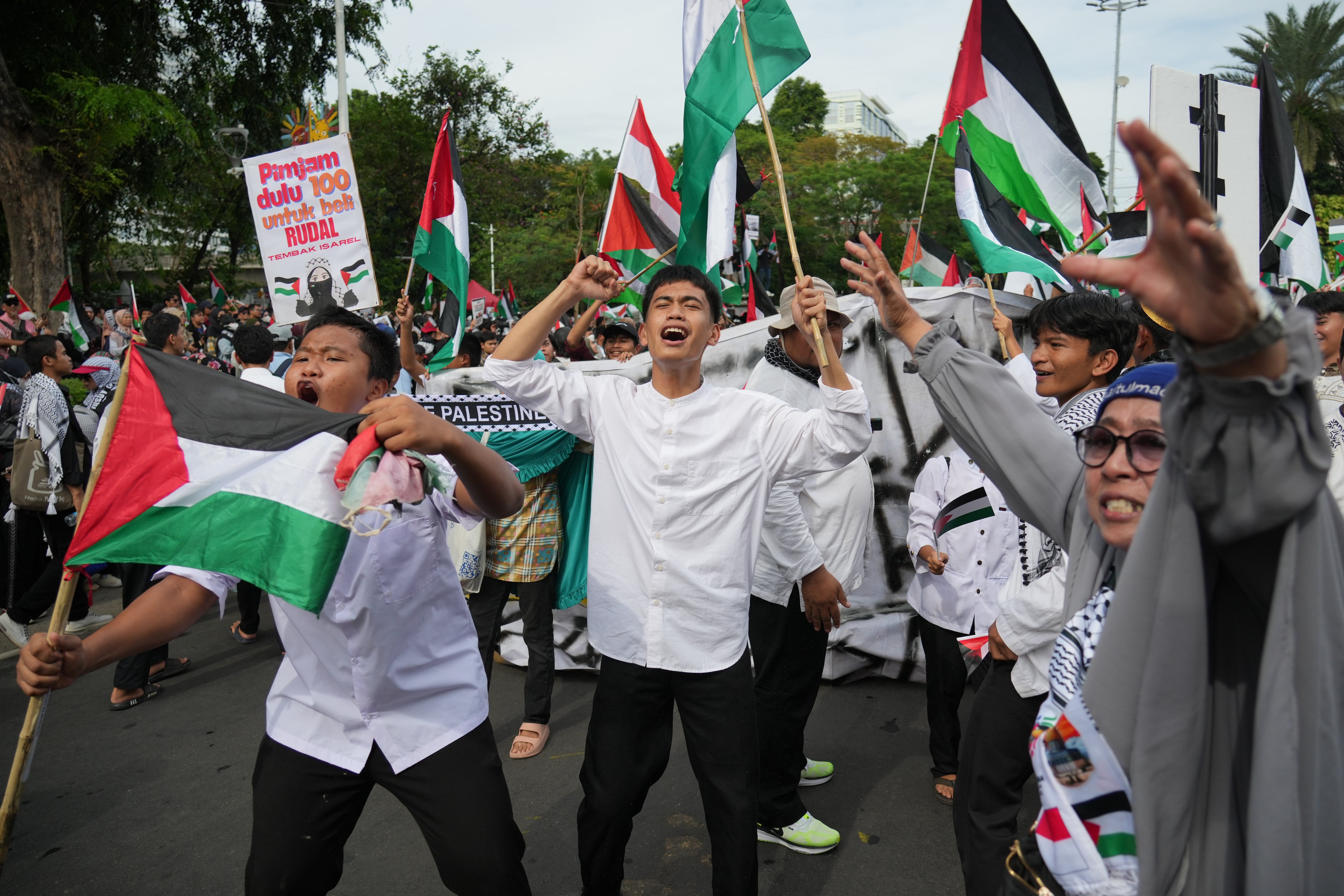 Manifestantes ondean banderas palestinas mientras corean consignas en una marcha. (AP Foto/Achmad Ibrahim)