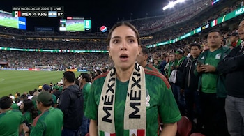 Una mujer con camiseta y bufanda de México mira hacia adelante con la boca abierta en un estadio de fútbol. El marcador FIFA World Cup 2026 muestra MEX vs ARG.