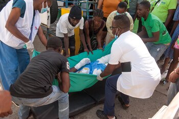 Varias personas cargan, este 15 de diciembre de 2021, a una persona herida tras la explosión de un camión para su traslado vía aérea a Puerto Príncipe, en Cap-Haitien (Haití). EFE/Johnson Sabin