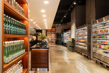 Interior de un supermercado moderno con estantes de madera con botellas, un mostrador de atención y largas vitrinas refrigeradas con productos