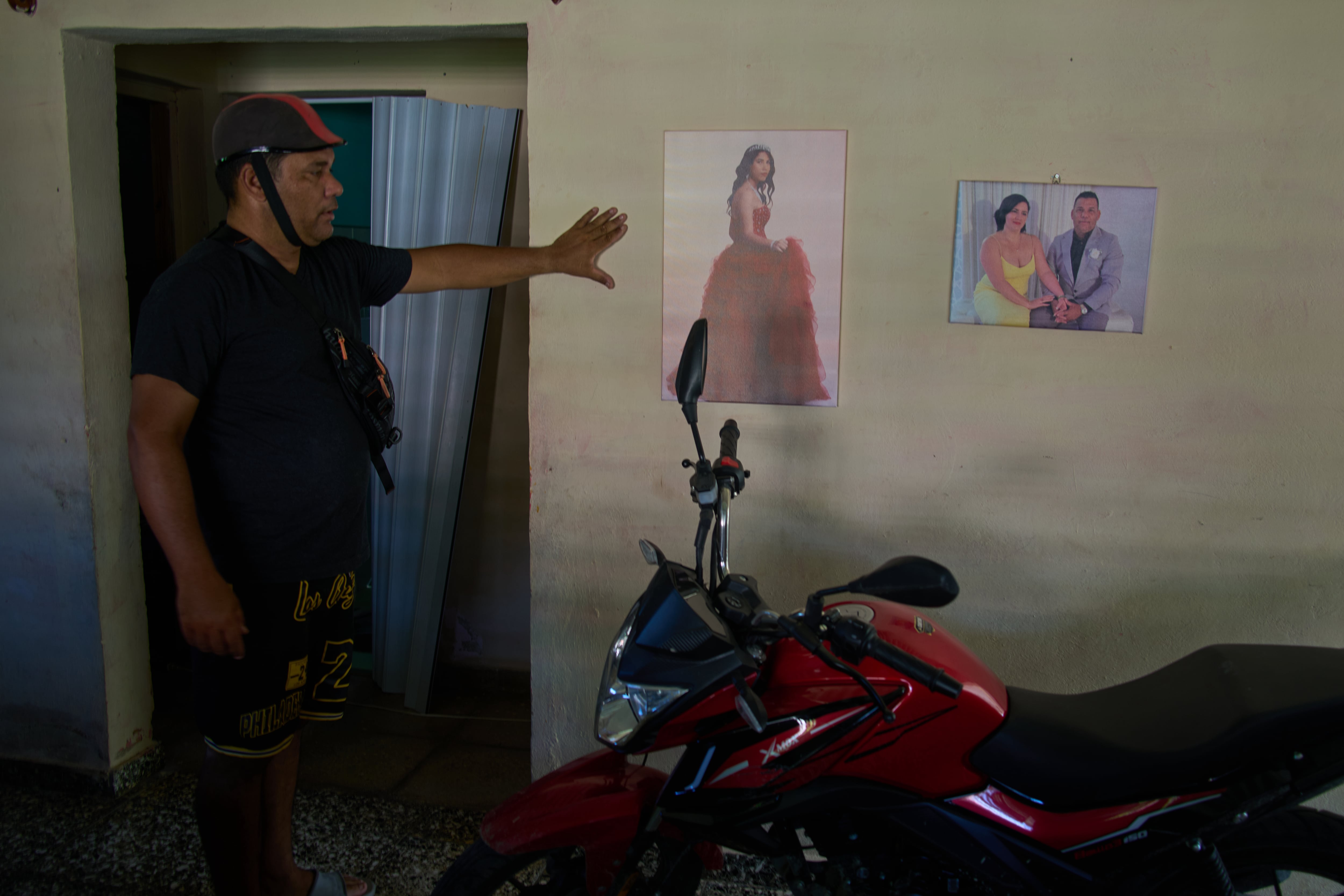Liexer De La Cruz junto a las fotografías de su hija, cuando cumplió 15 años, y otra junto a su esposa. (Infobae Cuba/AP Photo/Ramon Espinosa)