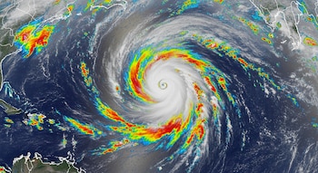 Imagen satelital de un huracán con nubes en espiral bien definidas sobre el océano. Zonas de agua cálida resaltadas en colores brillantes contrastan con el mar frío.