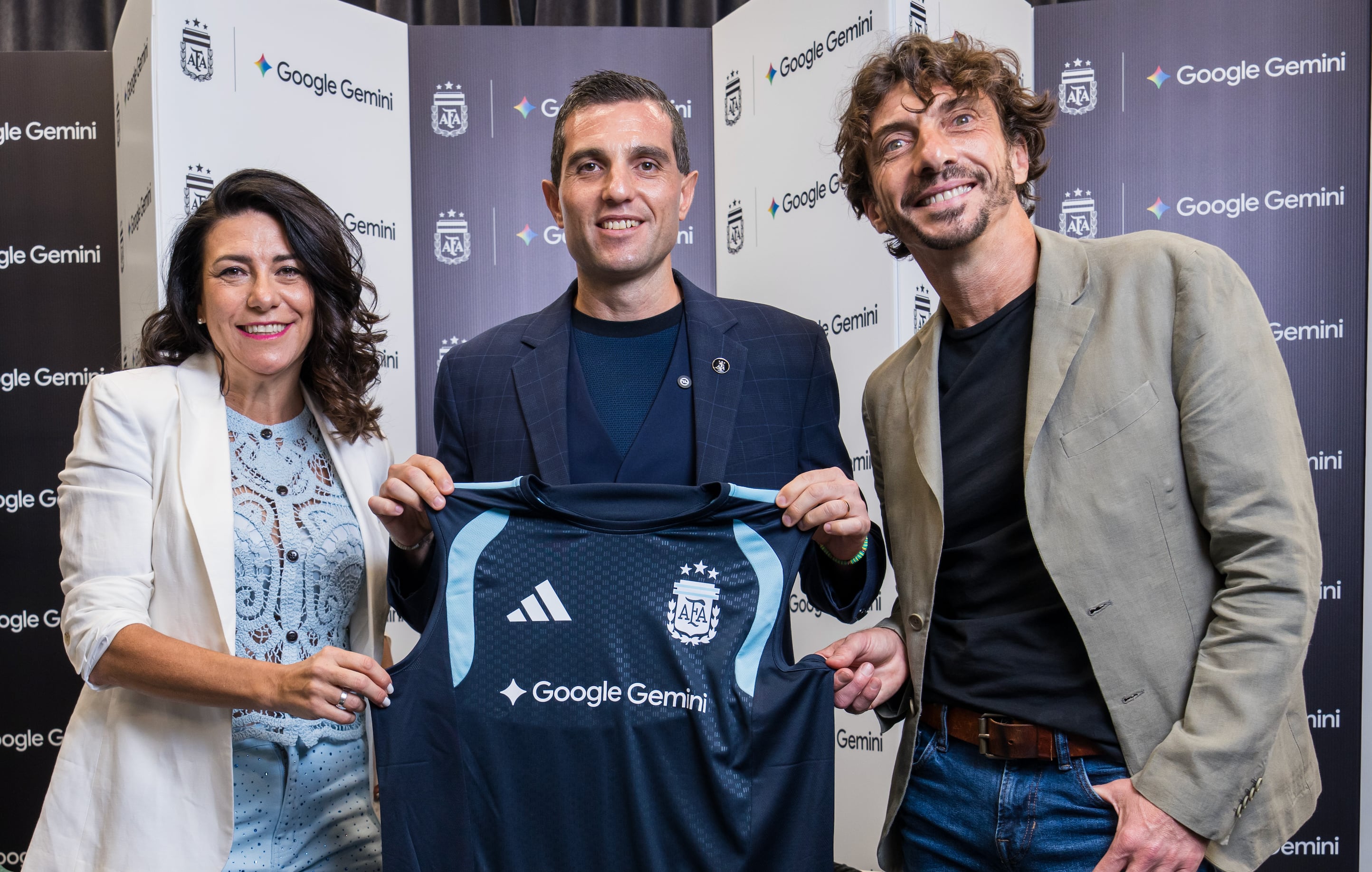 Florencia Sabatini de Google, Leandro Petersen de la AFA y Ramiro Sánchez de Google posan con la camiseta que lleva el logo de Google Gemini, celebrando el acuerdo de patrocinio principal para las selecciones argentinas durante 2026 y 2027. (AFA)