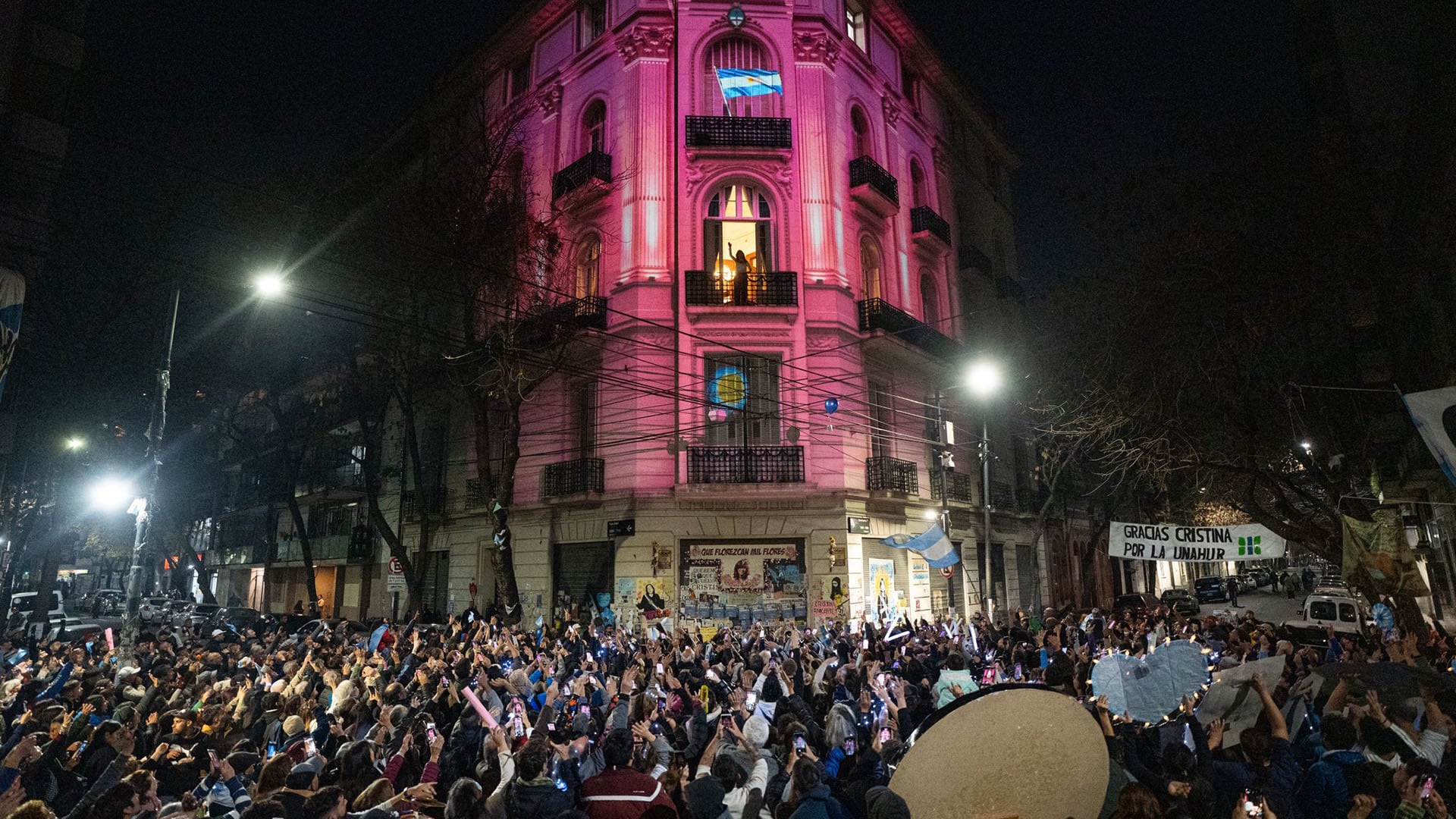 Cristina Kirchner saluda a sus militantes, mientras se proyecta la Casa Rosada sobre la fachada de su edificio