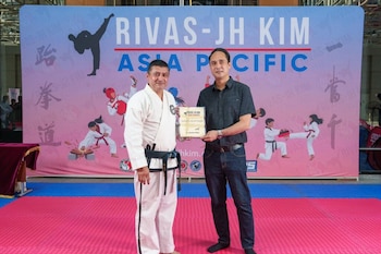El embajador Jaime José López Badía entrega un reconocimiento al doctor Santos Rivas durante la graduación de cinturones negros, resaltando el liderazgo salvadoreño en Asia.