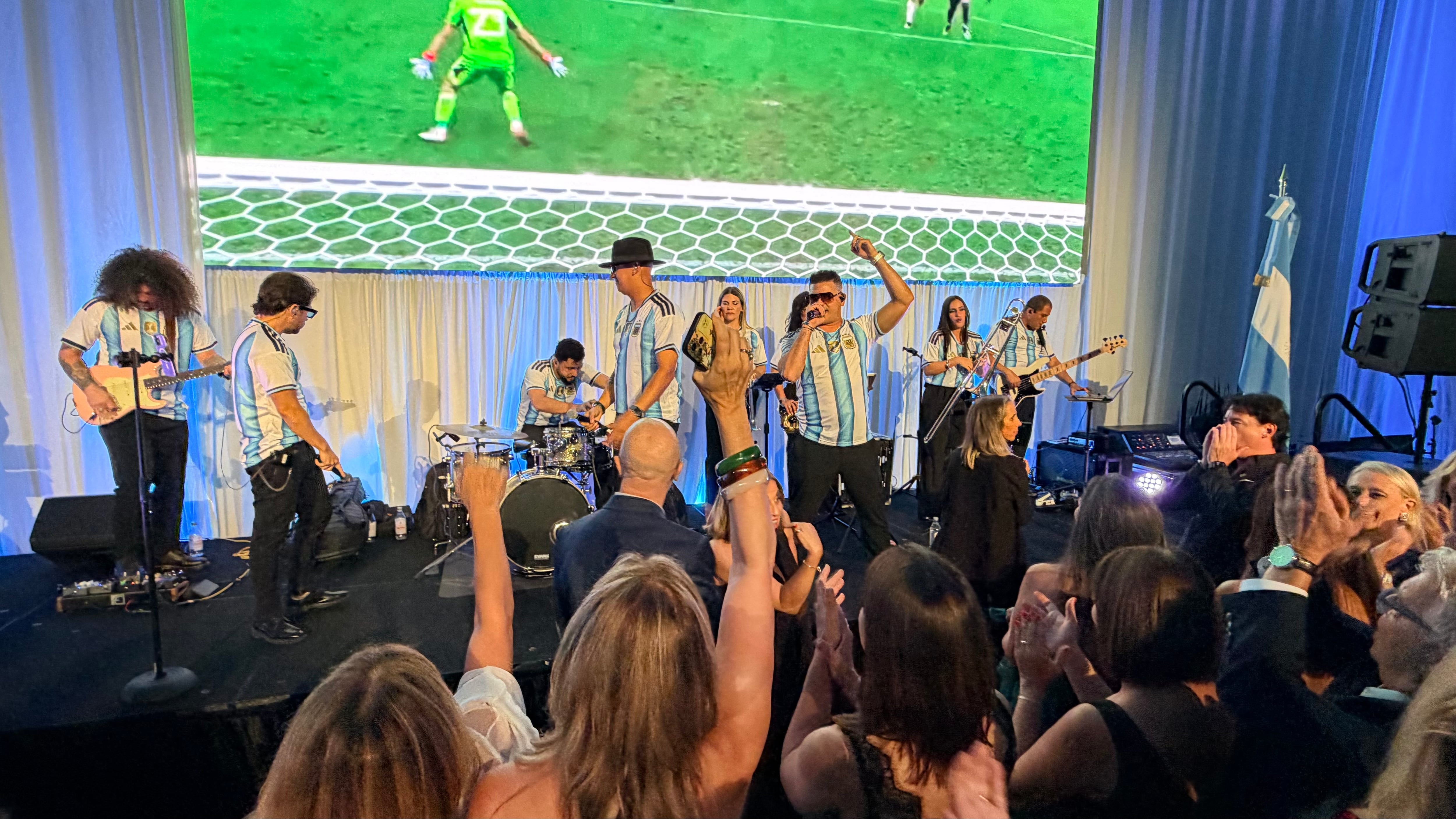 Una banda en camisetas de Argentina anima la gala anual de la Cámara Argentino-Americana de Comercio en Miami, mientras los asistentes disfrutan de la música y la pantalla de fútbol.