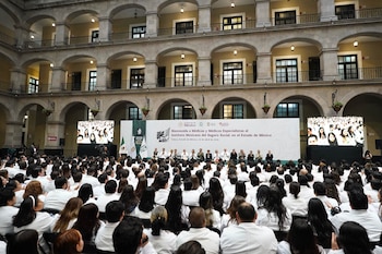Vista aérea de una gran convención de médicos con batas blancas en un auditorio interior con una gran fachada de piedra abovedada y balcones