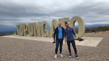 Frente al cartel de bienvenida