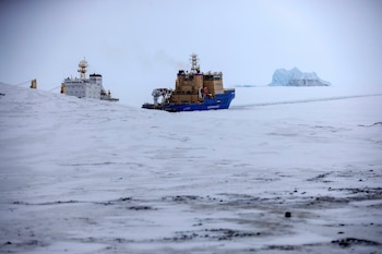 Un rompehielos le abre camino a un buque carguero con un iceberg al fondo en las inmediaciones de un puerto en la isla Alexandra Land,, cerca de Nagurskoye, Rusia (AP Foto/Alexander Zemlianichenko, Archivo)