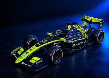 Automóvil de carreras monoplaza de color negro y amarillo fluorescente situado sobre una superficie oscura con luz azul lateral