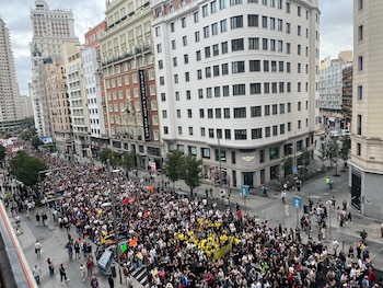 Vista aérea de miles de personas caminando por una amplia calle flanqueada por edificios urbanos en Madrid