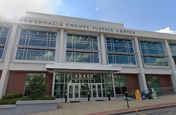Fachada de un edificio moderno con el letrero Monongalia County Justice Center, ventanales de vidrio y una entrada de cristal