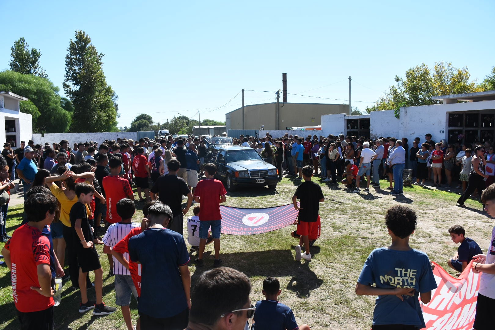 Los chicos del club desplegaron sus banderas ante el coche fúnebre, rodeados de nichos. Fotografía: Leo Galletto