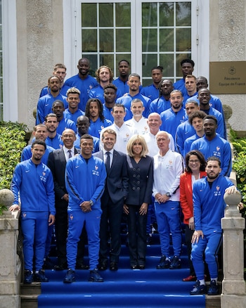 La Selección de Francia, junto a Emmanuel y Brigitte Macron, posa en una escalinata con alfombra azul frente a un edificio