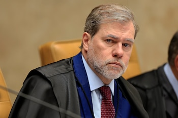 Retrato de Dias Toffoli vistiendo una toga negra con solapa azul y corbata roja con estampados