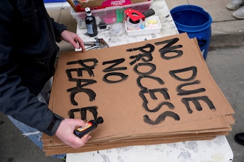 A protester prepares a placard outside Milwaukee Federal Building & U.S. Courthouse, after Wisconsin county judge Hannah Dugan was arrested by U.S. officials, charging her with helping a man in her court evade immigration authorities in an escalating dispute between President Donald Trump's administration and local officials over immigration enforcement, in Milwaukee, Wisconsin, U.S., April 25, 2025. REUTERS/Vincent Alban