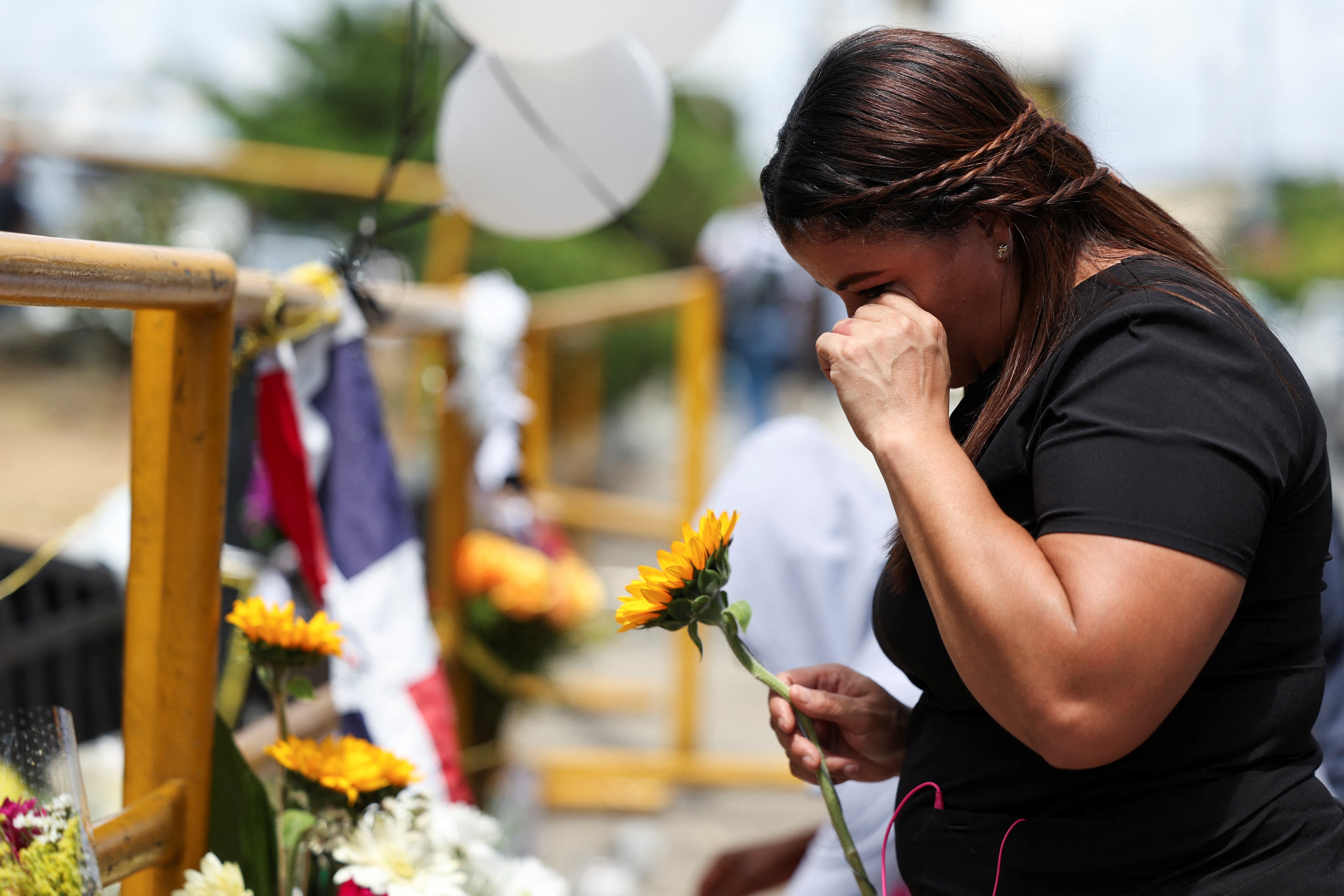 Una mujer reacciona mientras sostiene una flor, cerca del lugar del derrumbe del techo de la discoteca Jet Set, en Santo Domingo, República Dominicana, el 11 de abril de 2025. (REUTERS/Ricardo Arduengo)