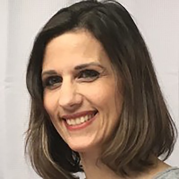 Primer plano de una mujer de mediana edad con cabello castaño, mirando ligeramente hacia la derecha y sonriendo