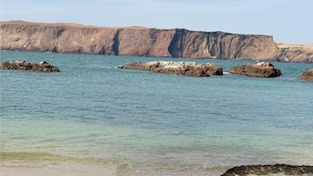 Visitantes disfrutan de las aguas tranquilas y el paisaje costero en Playa La Mina, uno de los balnearios más populares de la Reserva Nacional de Paracas.
