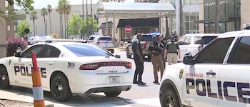 Vista de varias patrullas y oficiales de la Policía de Baton Rouge en una calle con un edificio al fondo y palmeras