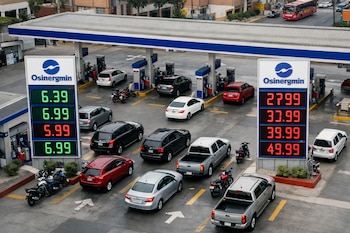 Vista aérea de una estación de servicio en Lima, Perú, con vehículos y dos grandes carteles digitales Osinergmin-Facilito que muestran precios de combustible en verde y rojo.