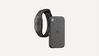 Un teléfono inteligente gris con un pequeño dispositivo rectangular rosado adherido a la parte trasera sobre un fondo blanco