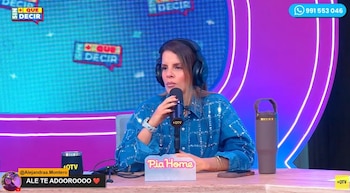 Mujer con chaqueta de mezclilla con brillos, auriculares y micrófono en un estudio de televisión. Hay un cartel "Pia Home" y una botella termo en la mesa