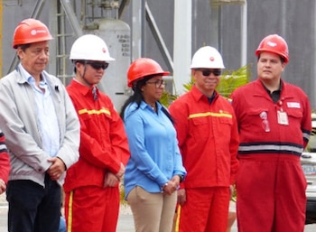 Cinco personas, incluyendo Delcy Rodríguez, Manuel Quevedo y Asdrúbal Chávez, con cascos de seguridad y ropa industrial, de pie frente a estructuras de una planta