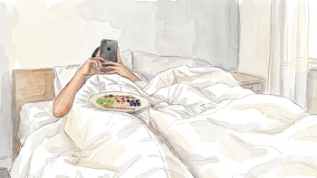 Ilustración de persona en la cama con edredón, sosteniendo un teléfono móvil. Un plato con cereales, kiwi, arándanos y plátano está en la cama.