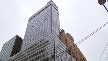 Rascacielos alto con fachada de vidrio, edificio beige, cielo nublado, poste de luz y cables