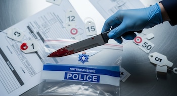 Una mano con guante azul sujeta un cuchillo ensangrentado sobre una bolsa de pruebas de la Policía de Nottinghamshire; en el fondo hay papeles y etiquetas numeradas.