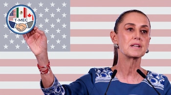 Claudia Sheinbaum, con blusa azul bordada, hablando ante micrófonos. De fondo, una bandera de Estados Unidos y un logo del T-MEC en círculo.