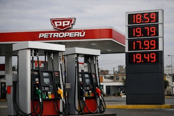 Una estación de servicio Petroperú en Lima, Perú, con surtidores de combustible en primer plano y un cartel digital mostrando precios altos en rojo.