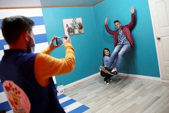 Unos visitantes sonríen y posan dentro de una casa construida al revés en Guatavita, Colombia. Enero 23, 2022. REUTERS/Luisa Gonzalez