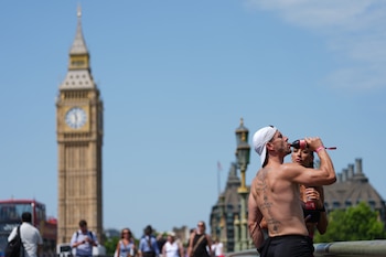 Un hombre bebe sobre el puente de Westminster mientras se pronostica una ola de calor para el martes 23 de junio de 2026, en Londres. (AP Foto/Kirsty Wigglesworth)