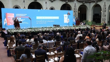 El Presidente Bernardo Arévalo de Guatemala habla desde un podio en un evento formal con una gran pantalla de fondo y una audiencia sentada