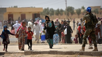 Una mujer camina junto a sus hijos bajo la custodia de un soldado del ejército iraquí. (Reuters)