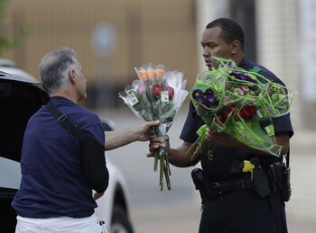 Un oficial de Dallas reciben unas flores como homenaje tras la matanza (AP)