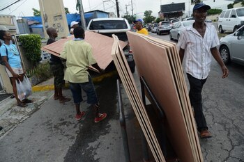 Personas transportan láminas de madera